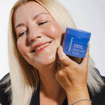 Smiling woman holding a jar of MenoMora Embrace menopause support supplement