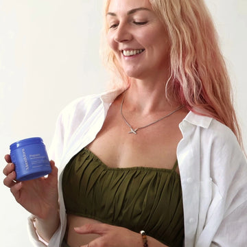 Smiling woman holding a jar of MenoMora Prepare perimenopause support supplement