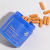 Blue container of MenoMora Thrive supplements with orange capsules on a light gray background